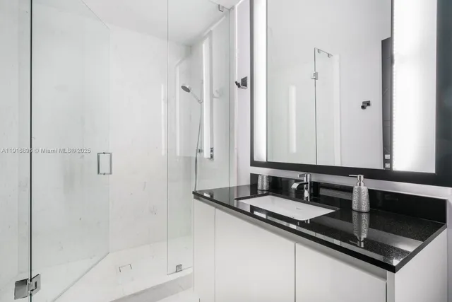 a bathroom with a granite countertop sink a mirror and a shower