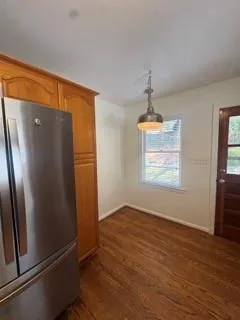 an empty room with wooden floor cabinet and windows