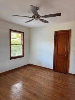 an empty room with wooden floor closet and windows