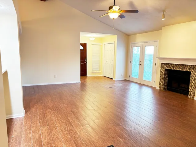 a view of an empty room with wooden floor and a fireplace
