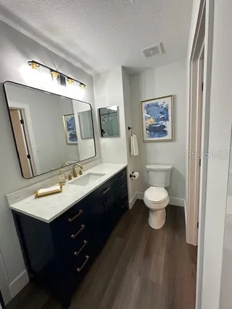 a bathroom with a toilet sink double vanity granite and mirror