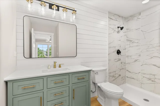 a bathroom with a granite countertop toilet sink and mirror