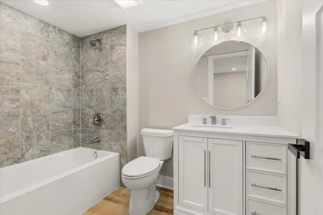 a bathroom with a toilet a sink a mirror a bathtub and vanity