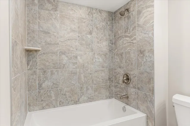 a bath tub sitting next to a white toilet and a shower