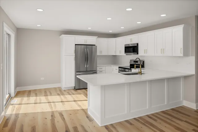 a kitchen with stainless steel appliances a sink a stove a refrigerator and cabinets