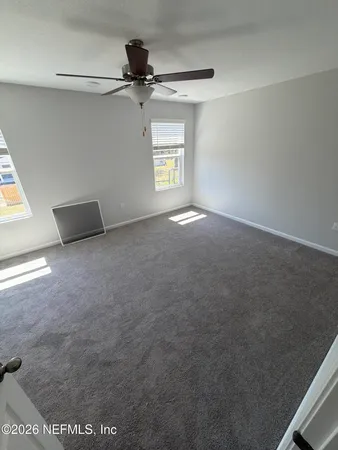 an empty room with wooden floor chandelier fan and windows
