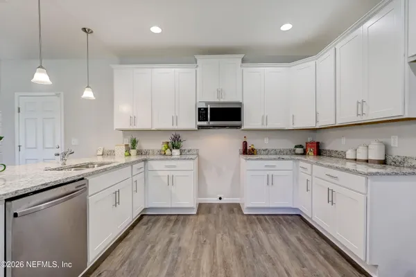 a kitchen with granite countertop white cabinets white stainless steel appliances with a sink and dishwasher