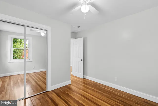 a view of an empty room with window wooden floor and a chandelier fan