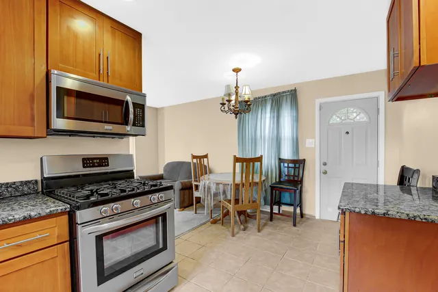 a kitchen with stainless steel appliances granite countertop a stove top oven a sink dishwasher a dining table and chairs with wooden floor