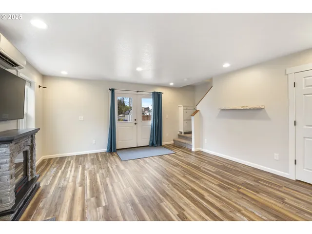 an empty room with wooden floor and a flat screen tv