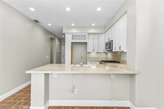 a large white kitchen with kitchen island a sink appliances and cabinets