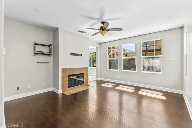 a view of a livingroom with a fireplace a ceiling fan and windows