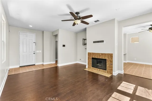 an empty room with wooden floor a fireplace and windows