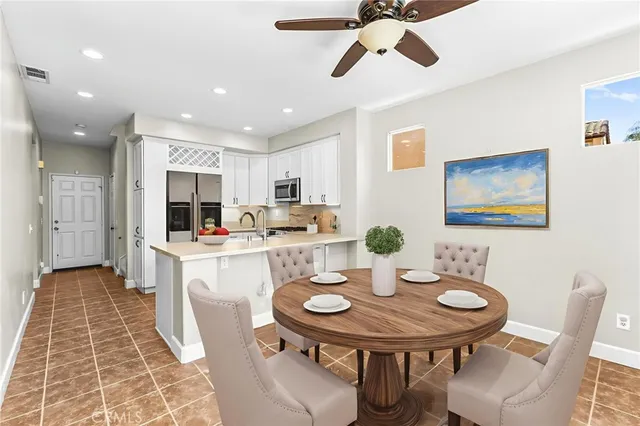 a kitchen with stainless steel appliances kitchen island granite countertop a dining table chairs and white cabinets