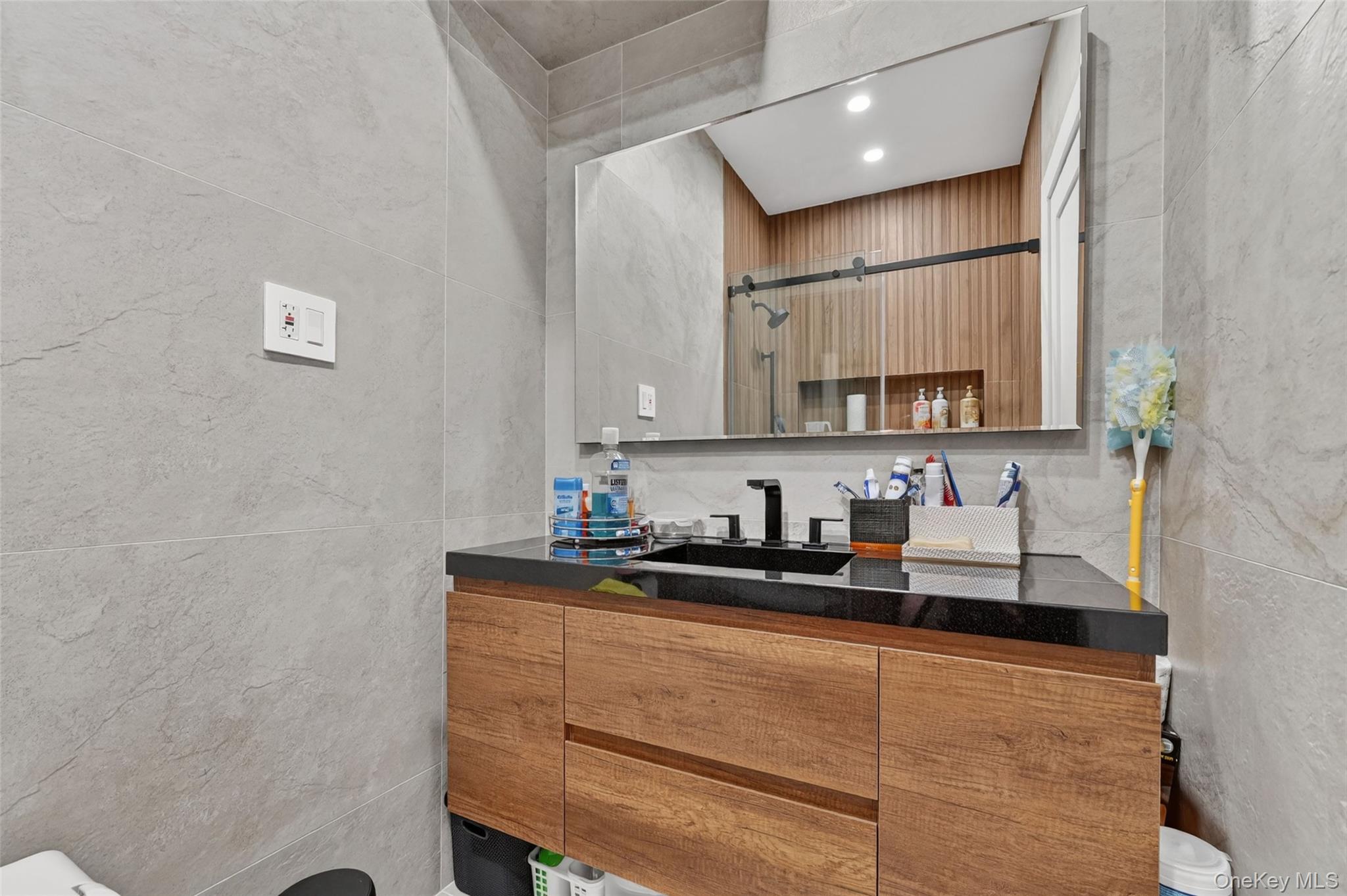 65 Wildway Bronxville, NY 10708 - Photo 22 of 42 Modern bathroom vanity with wood-finish cabinetry, black countertop, and undermount sink