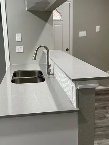 a close view of a sink and dishwasher with wooden floor