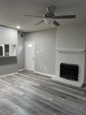 a view of a room a ceiling fan a fireplace and entryway