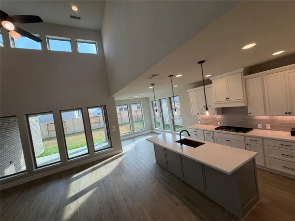 a kitchen that has a lot of cabinets a sink and wooden floor
