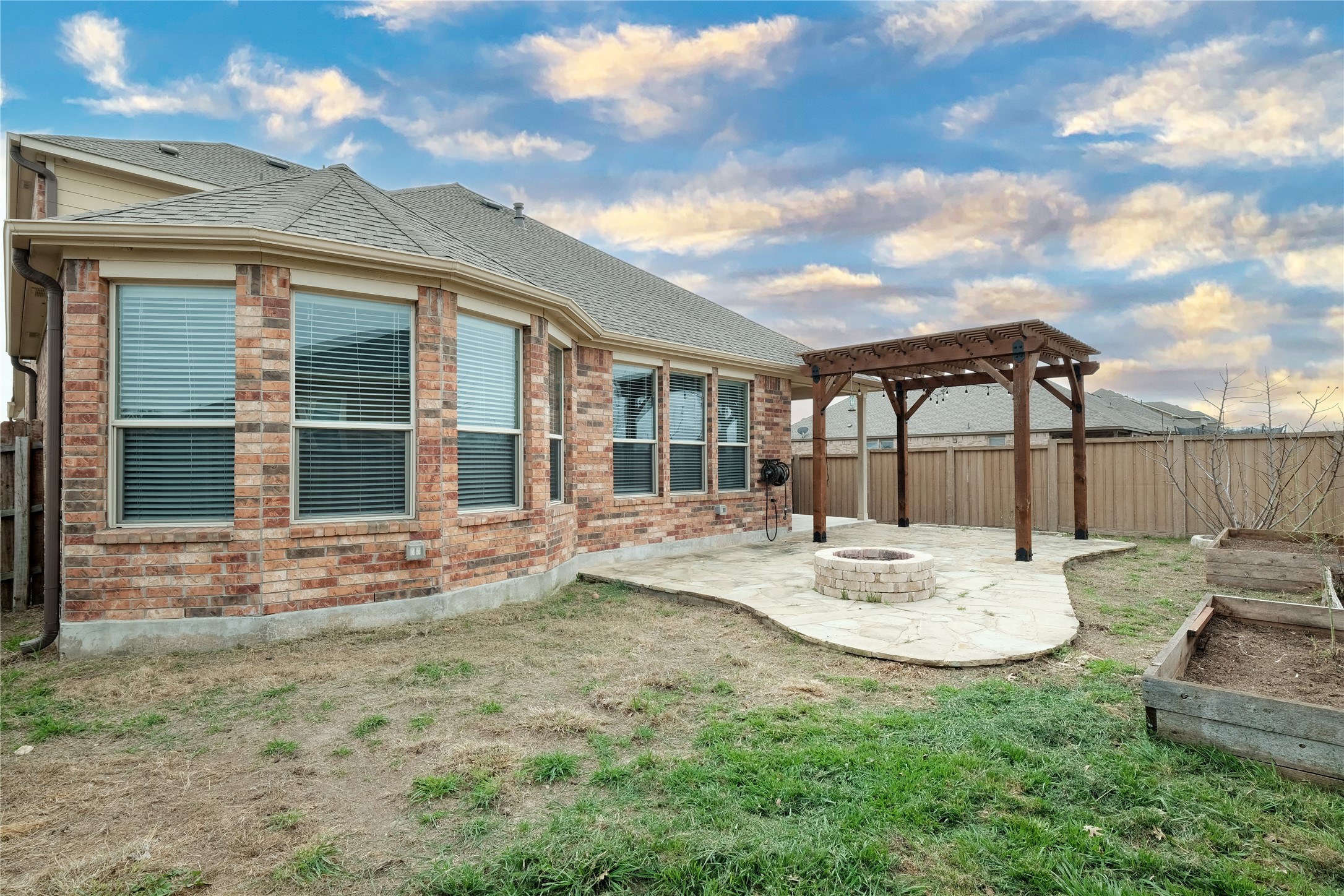 1804 Elaina Loop Leander, TX 78641 - Photo 12 of 12 Back of house with a patio area, a fenced backyard, a shingled roof, a pergola, and an outdoor fire pit
