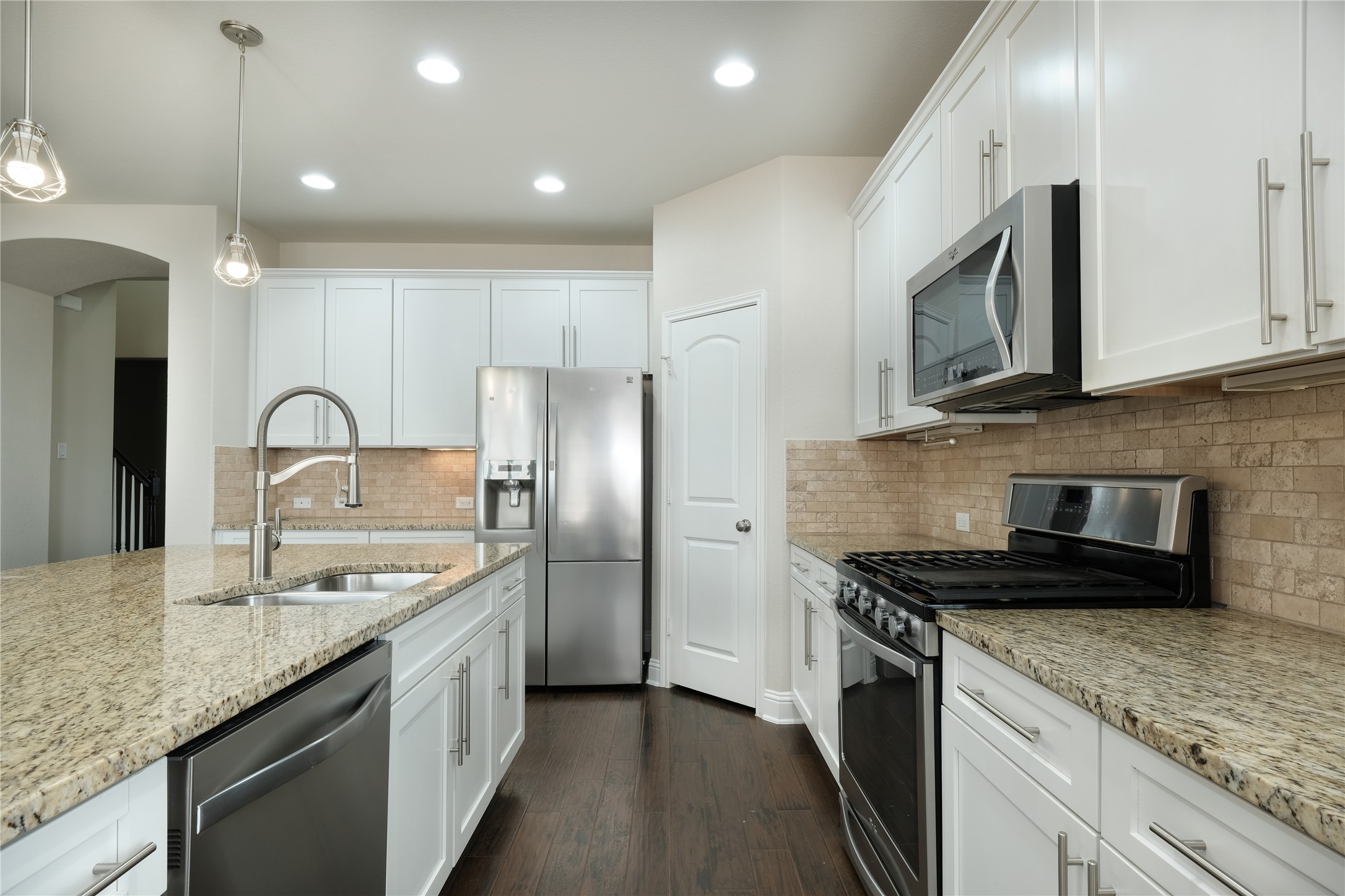 1804 Elaina Loop Leander, TX 78641 - Photo 3 of 12 Kitchen with stainless steel appliances, white cabinetry, and dark wood finished floors