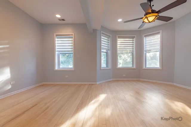 an empty room with windows and chandelier fan