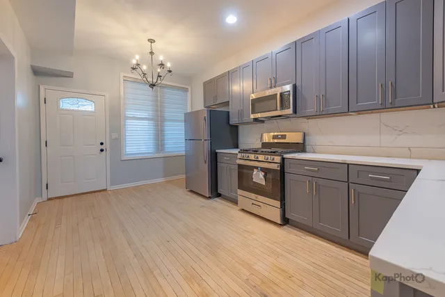 a kitchen with stainless steel appliances granite countertop a refrigerator oven a sink dishwasher and wooden cabinets with wooden floor