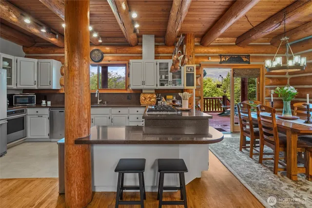 a kitchen with stainless steel appliances granite countertop a table chairs and wooden floors