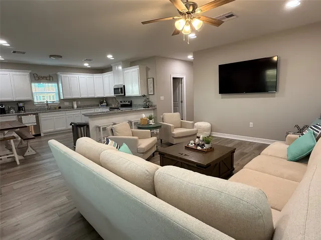 a living room with furniture kitchen view and a flat screen tv