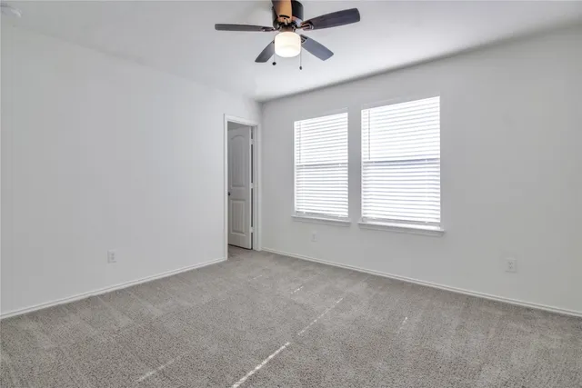 an empty room with a ceiling fan and carpet