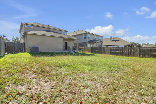 a view of a house with a yard and a large tree