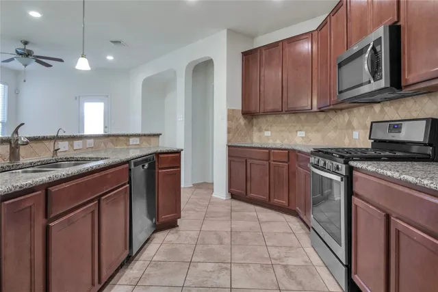 a kitchen with stainless steel appliances granite countertop a stove sink and cabinets