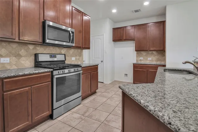 a kitchen with kitchen island granite countertop stainless steel appliances and cabinets
