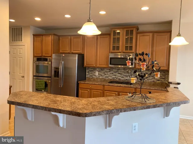 a kitchen with stainless steel appliances granite countertop a sink refrigerator and cabinets