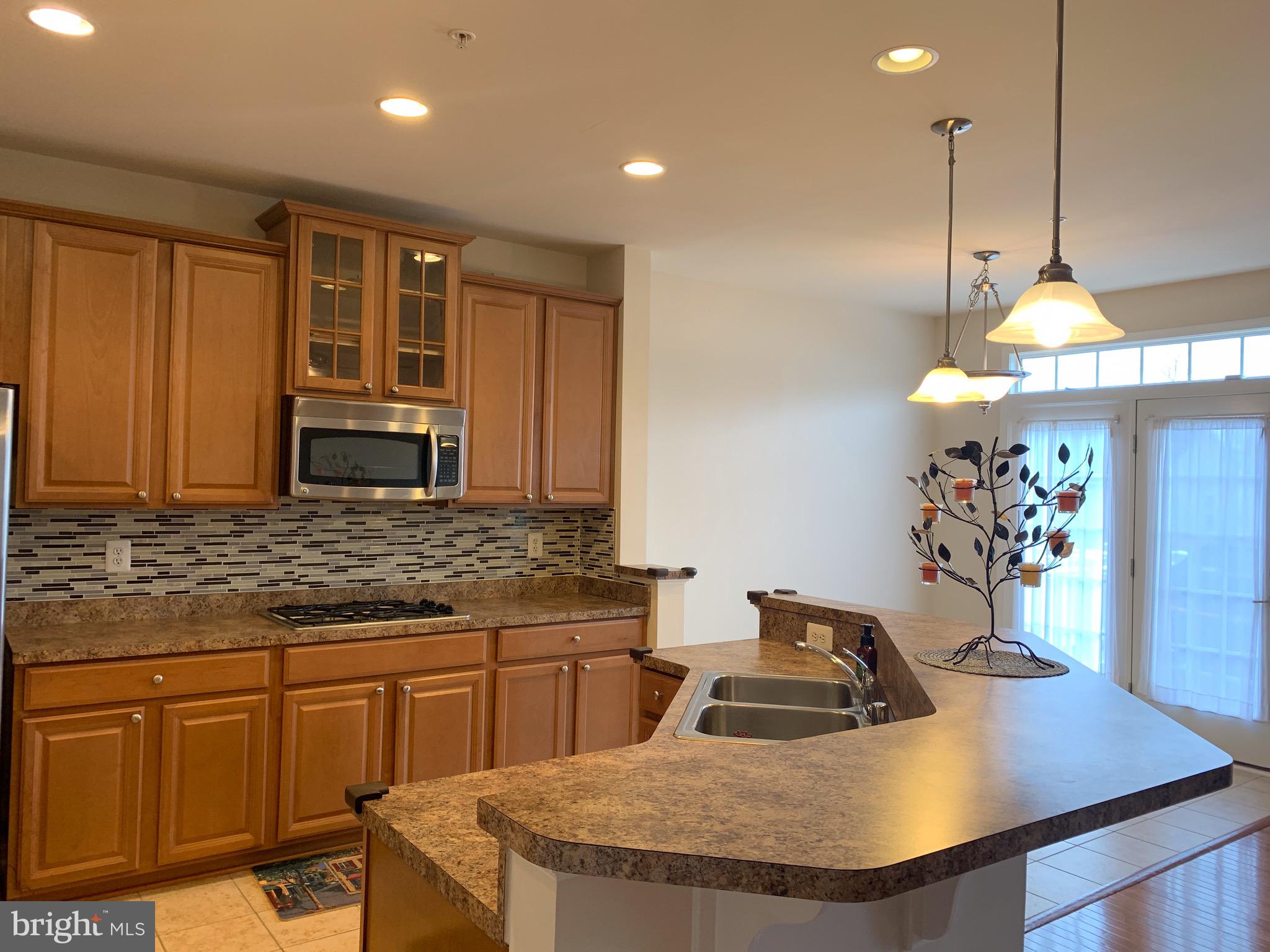 2816 Admiral Ridge Road Accokeek, MD 20607 - Photo 16 of 38 a kitchen with kitchen island granite countertop a sink a stove and a wooden cabinets