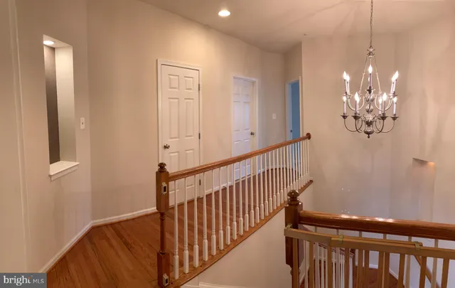 a view of a hallway with wooden floor and chandelier