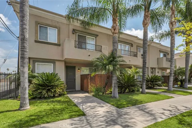 a view of a house with a yard and palm trees