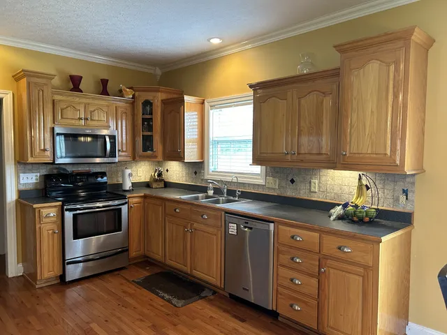 a kitchen with stainless steel appliances kitchen island granite countertop a stove a sink and a refrigerator