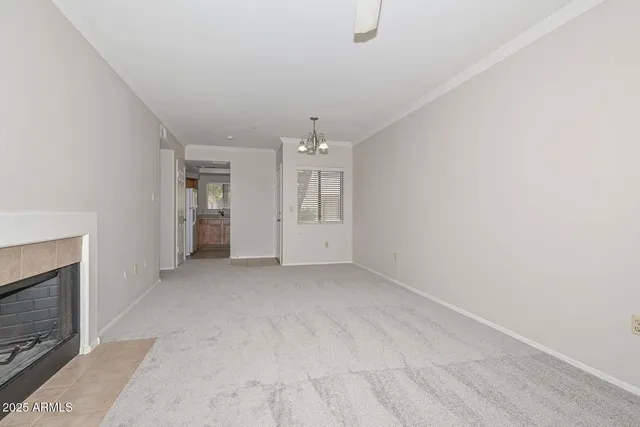 an empty room with chandelier and fireplace