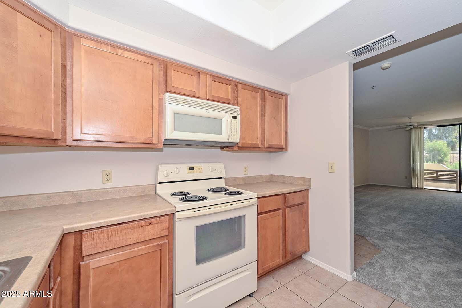 750 East Northern Avenue, Unit 1094 Phoenix, AZ 85020 - Photo 10 of 35 a kitchen with stainless steel appliances granite countertop white cabinets and a stove top oven