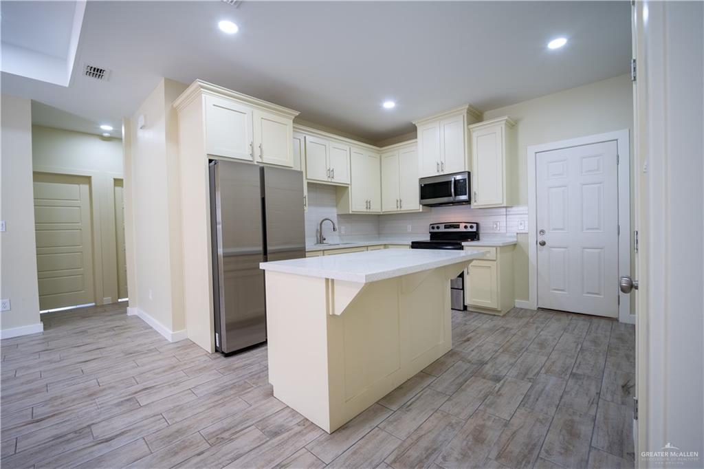 3086 Briggs Road, Unit B Weslaco, TX 78596 - Photo 10 of 15 Kitchen featuring stainless steel appliances, light wood-type flooring, a center island, a kitchen bar, and recessed lighting
