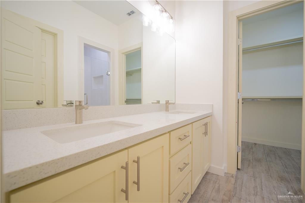 3086 Briggs Road, Unit B Weslaco, TX 78596 - Photo 12 of 15 Bathroom featuring a walk in closet, double vanity, and light wood-style flooring