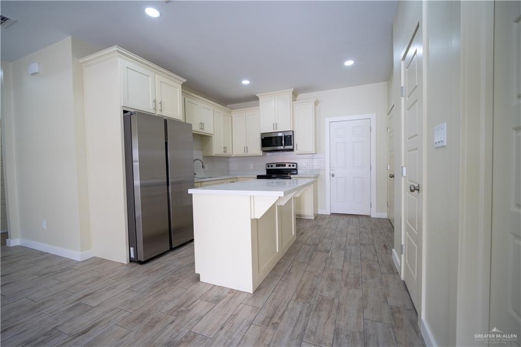 3086 Briggs Road, Unit B Weslaco, TX 78596 - Photo 3 of 15 Kitchen featuring stainless steel appliances, light wood-style flooring, a center island, white cabinets, and recessed lighting