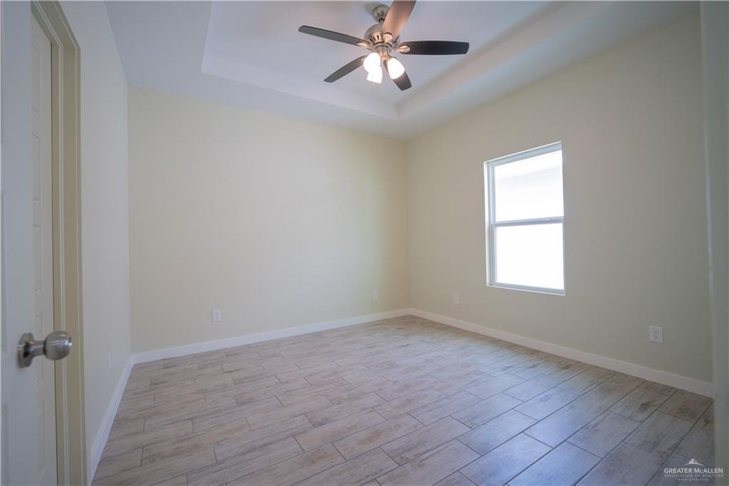 3086 Briggs Road, Unit B Weslaco, TX 78596 - Photo 5 of 15 Unfurnished room with wood finish floors, a ceiling fan, and a tray ceiling