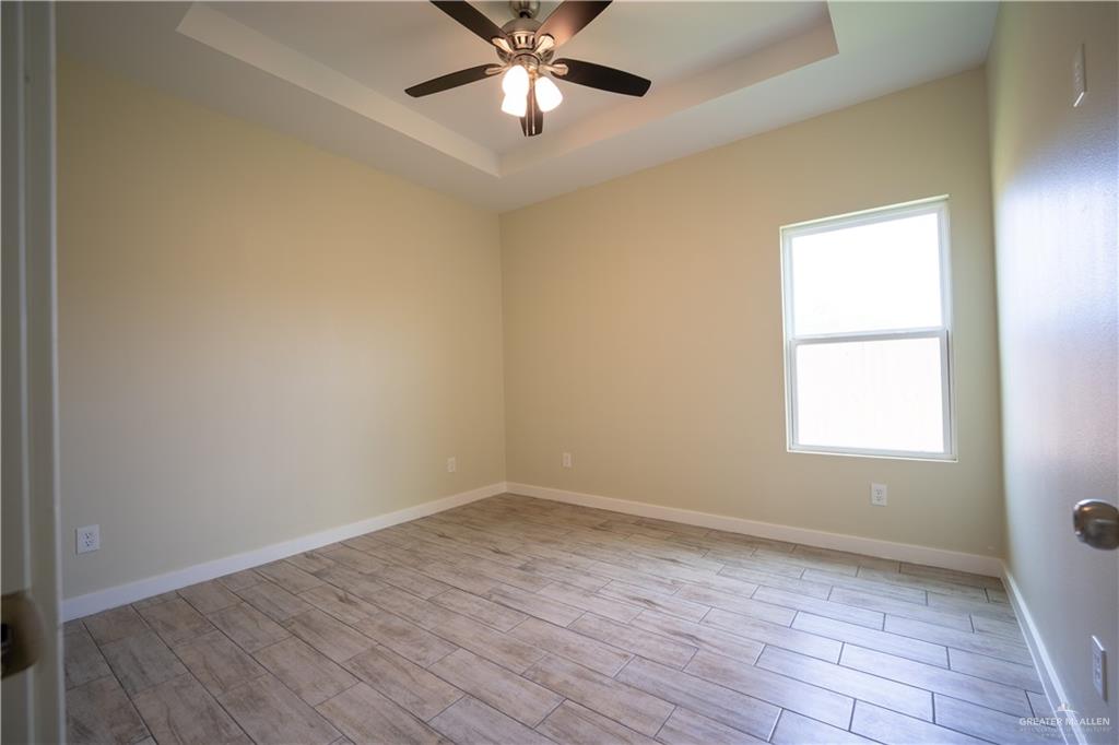 3086 Briggs Road, Unit B Weslaco, TX 78596 - Photo 7 of 15 Unfurnished room with wood tiled floors, a tray ceiling, and ceiling fan