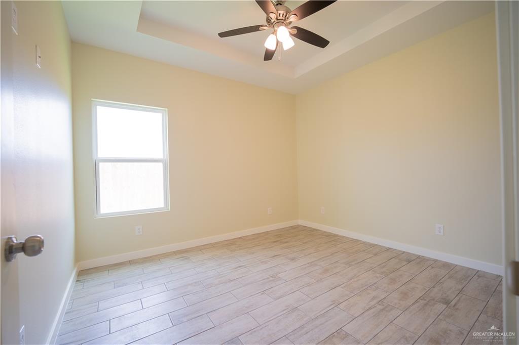 3086 Briggs Road, Unit B Weslaco, TX 78596 - Photo 8 of 15 Spare room featuring a raised ceiling, wood tiled floors, and a ceiling fan