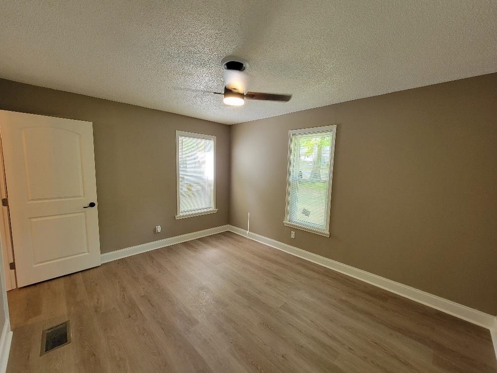 913 Chambliss Road Memphis, TN 38116 - Photo 10 of 16 Spacious room featuring wood-finish flooring, two windows with blinds, a ceiling fan with light fixture, and a solid white door with black hardware