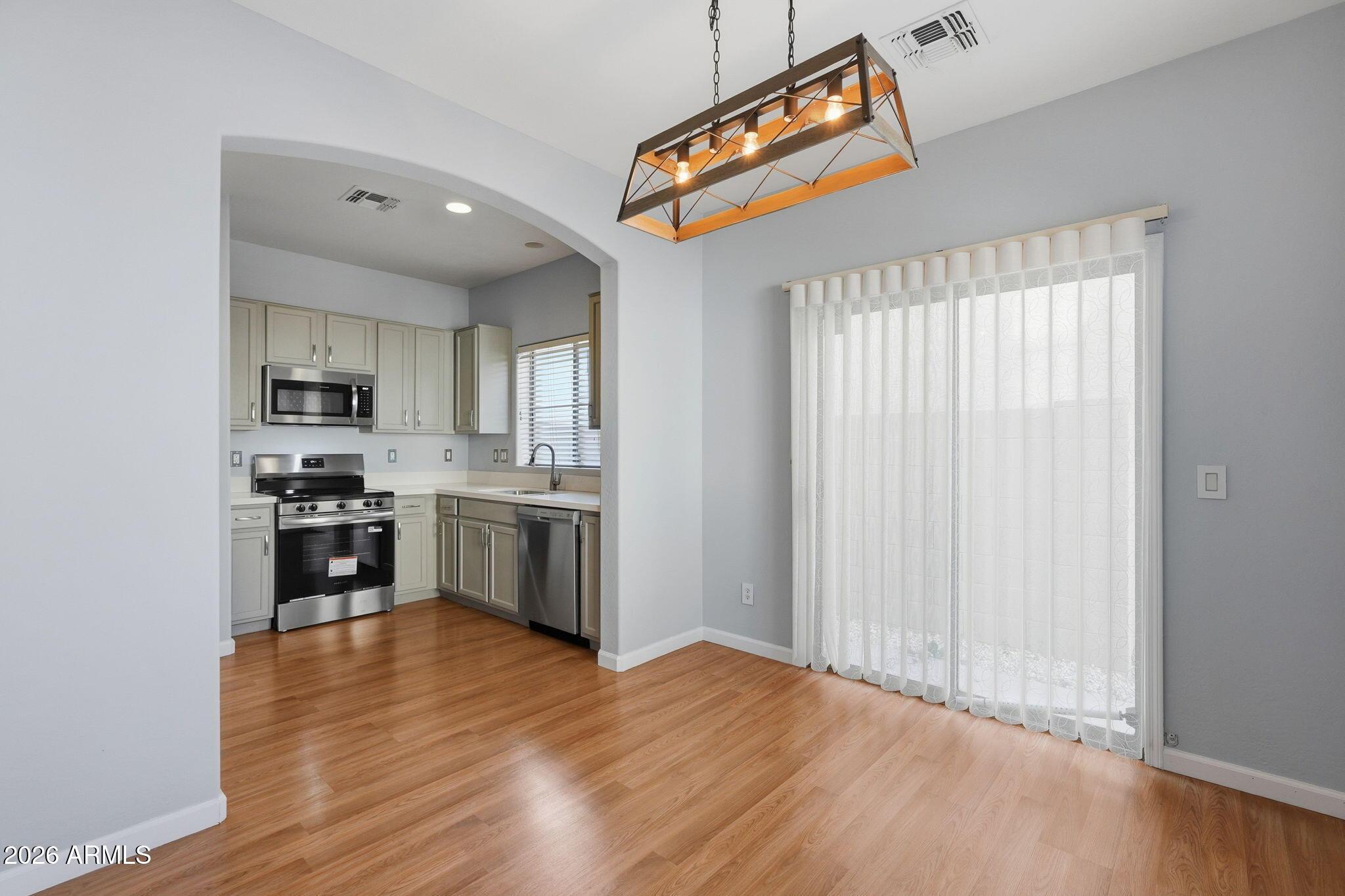 4678 East Redfield Road Gilbert, AZ 85234 - Photo 5 of 31 a kitchen with stainless steel appliances granite countertop a refrigerator a stove top oven a sink dishwasher and wooden floor