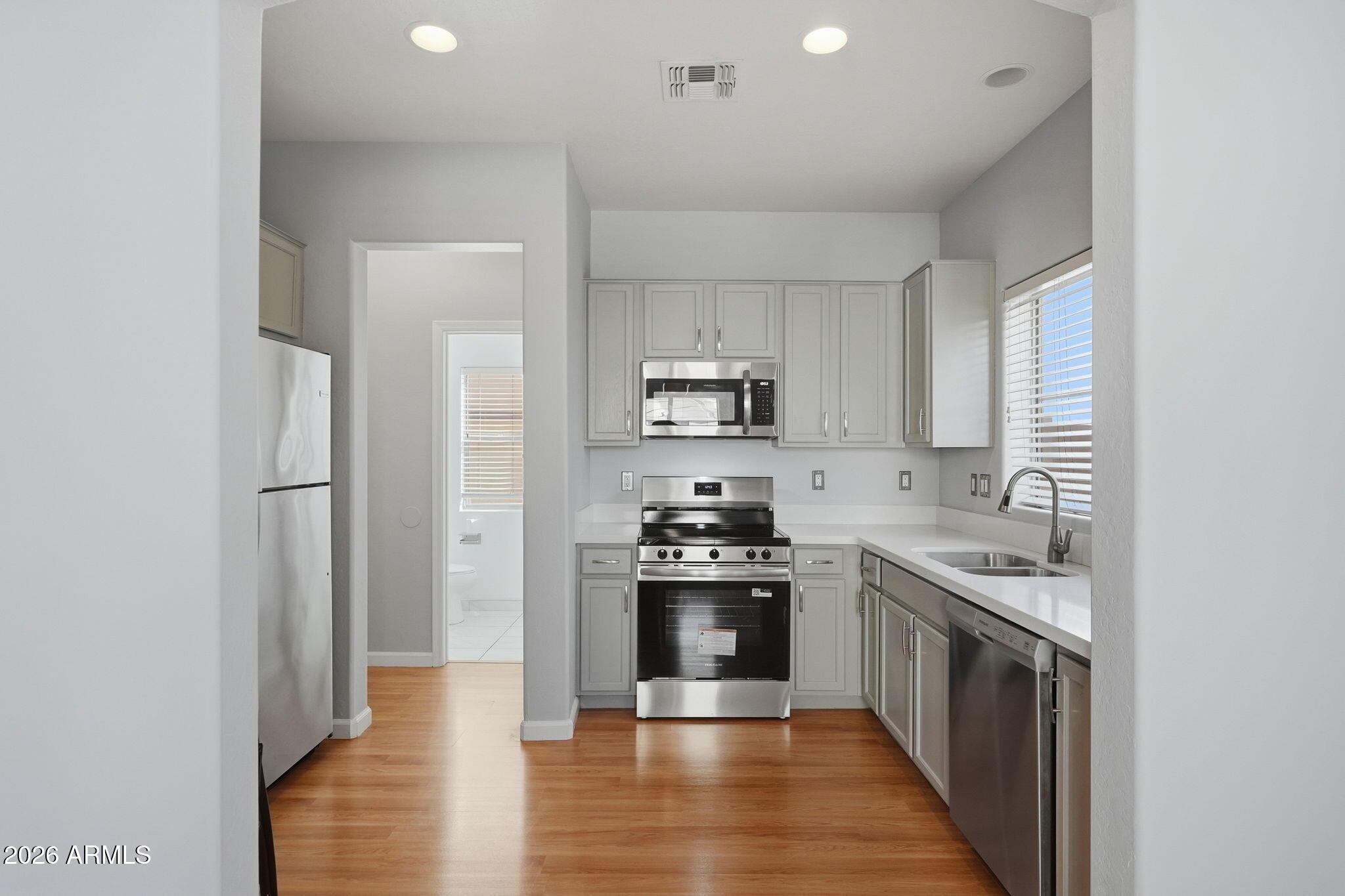 4678 East Redfield Road Gilbert, AZ 85234 - Photo 6 of 31 a kitchen with stainless steel appliances granite countertop white cabinets a stove top oven with wooden floor