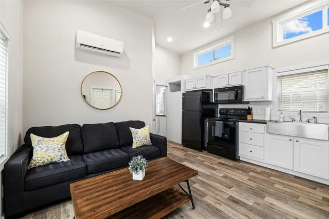 a living room with stainless steel appliances furniture a dining table and a window