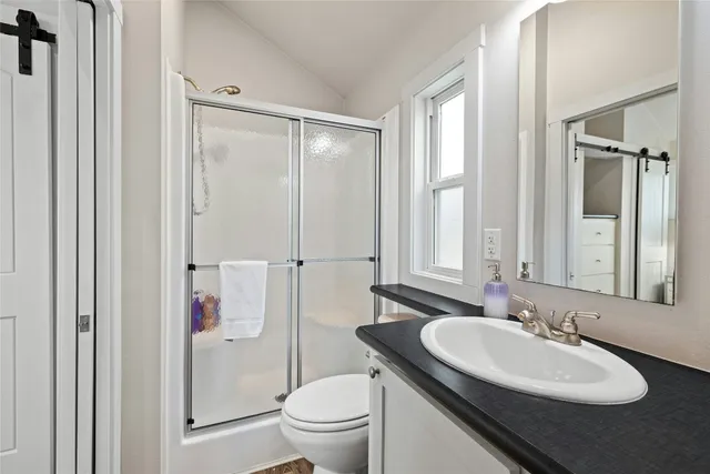 a bathroom with a granite countertop sink vanity mirror and toilet